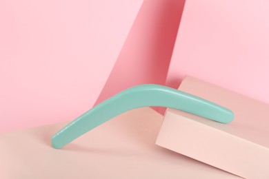 Creative composition with turquoise wooden boomerang on pink background