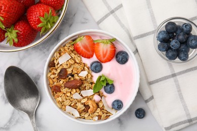Photo of Tasty granola, yogurt and fresh berries in bowl served on white marble table, flat lay. Healthy breakfast