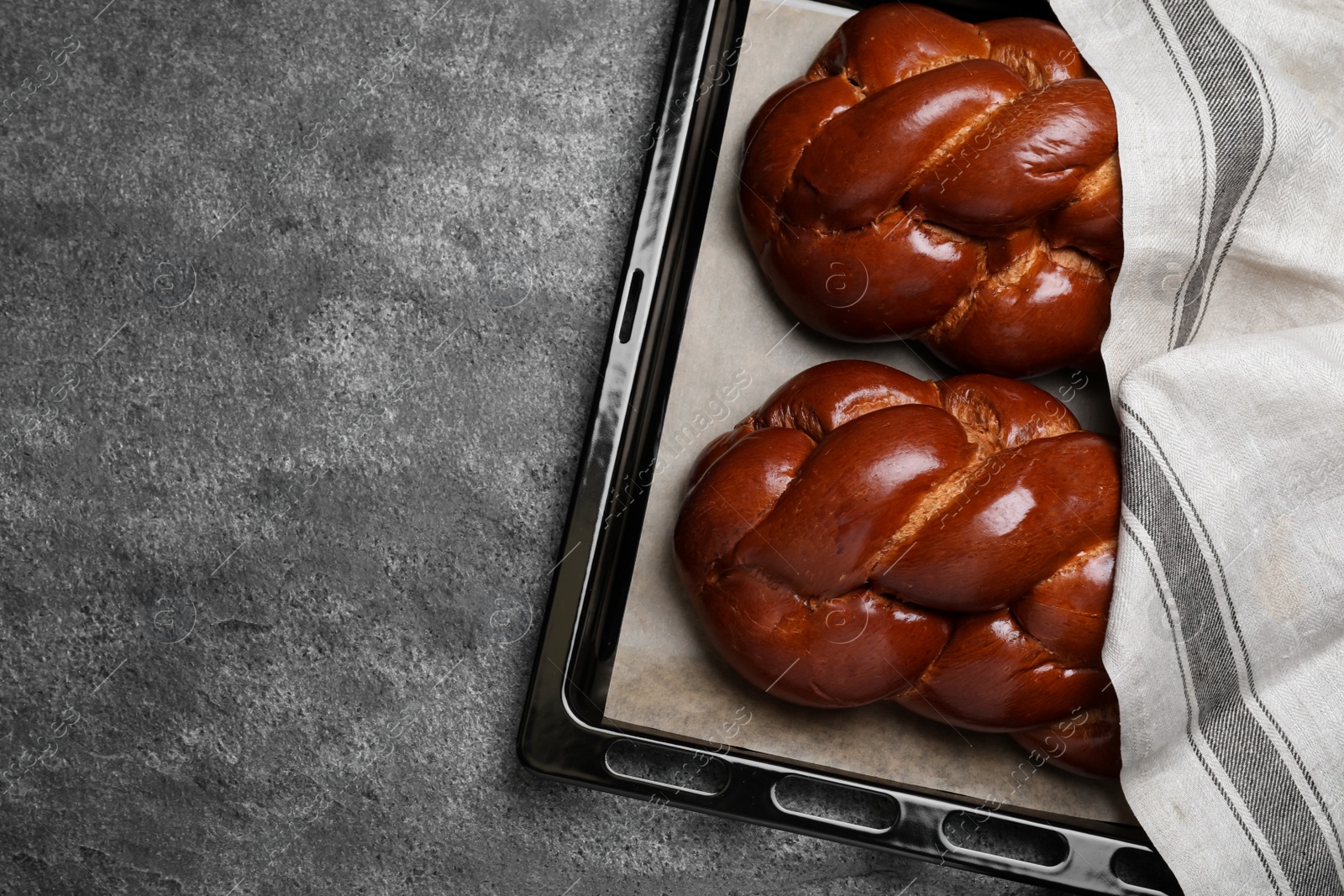 Photo of Homemade braided bread on grey table, top view. Traditional challah