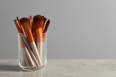 Photo of Set of professional makeup brushes on table against grey background, space for text