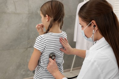 Photo of Doctor examining coughing girl in hospital. Cold symptoms