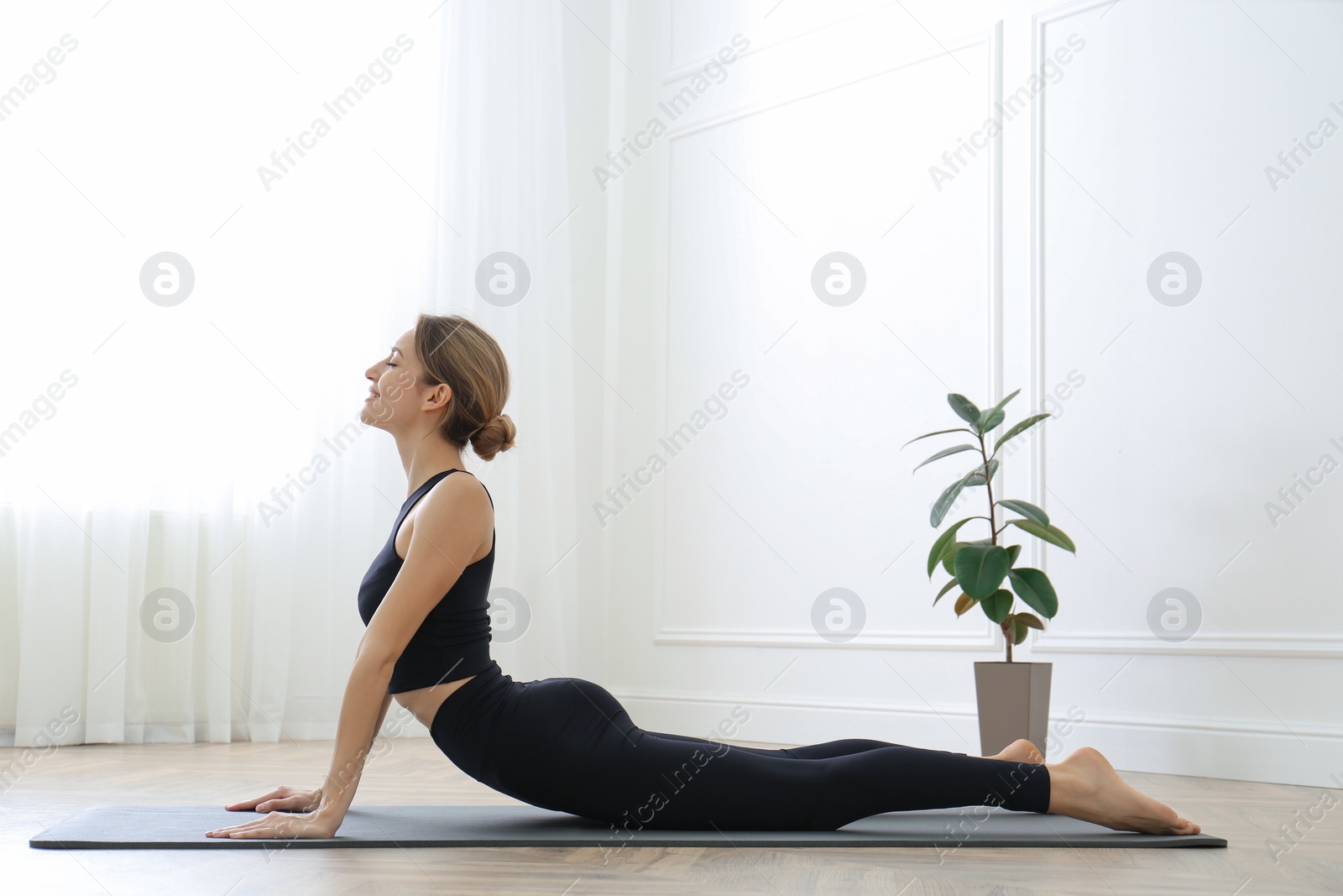 Photo of Young woman practicing high cobra asana in yoga studio. Bhujangasana pose