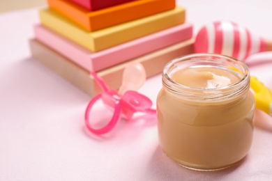 Photo of Healthy baby food in glass jar on table, closeup. Space for text