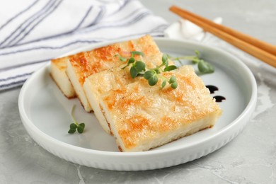 Photo of Delicious turnip cake with microgreens served on grey table