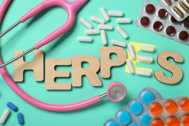 Photo of Word Herpes made of wooden letters, different pills and stethoscope on turquoise background, flat lay