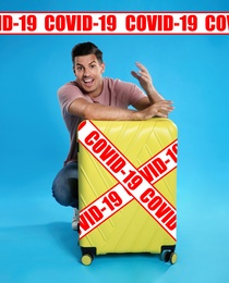 Image of COVID-19 pandemic, travel during coronavirus outbreak. Excited man with suitcase on blue background