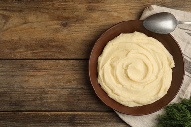 Photo of Freshly cooked homemade mashed potatoes and spoon on wooden table, top view. Space for text