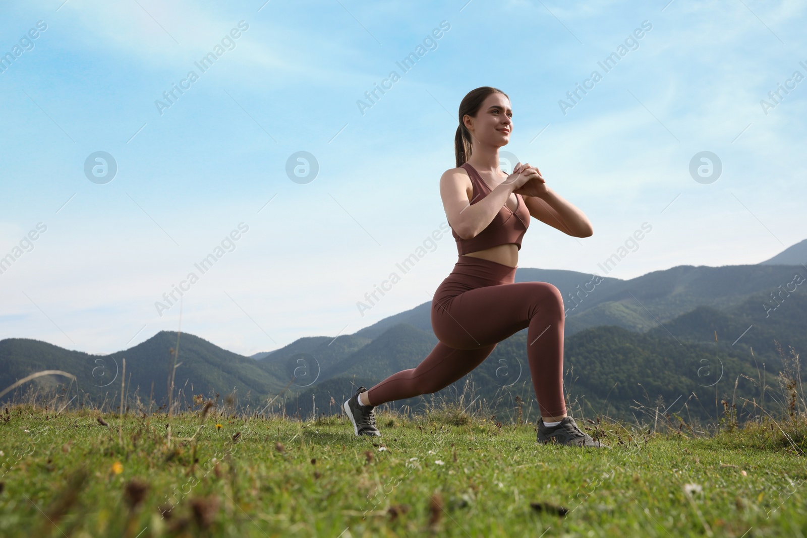 Photo of Young woman doing morning exercise in mountains, space for text