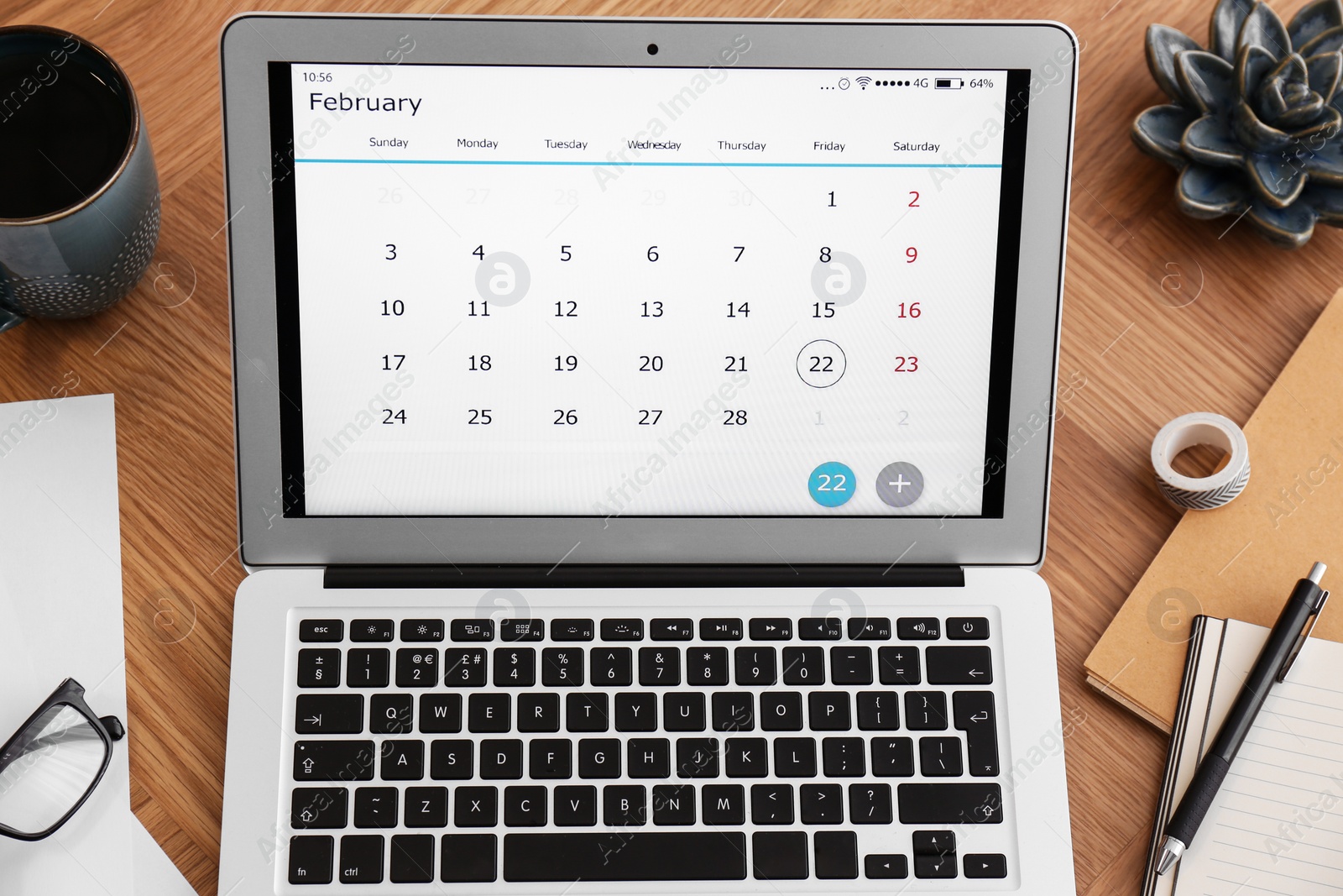 Photo of Modern laptop with calendar on wooden table, above view