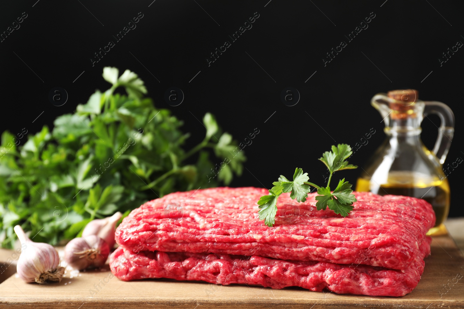 Photo of Raw ground meat, garlic, oil and parsley on table