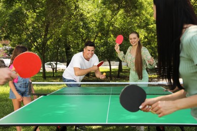 Photo of Happy family with child playing ping pong in park