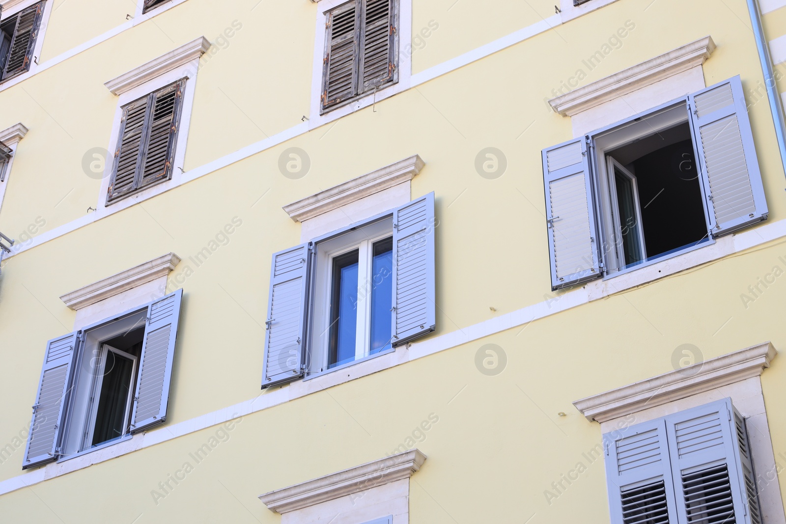 Photo of Residential building with windows and wooden shutters, low angle view