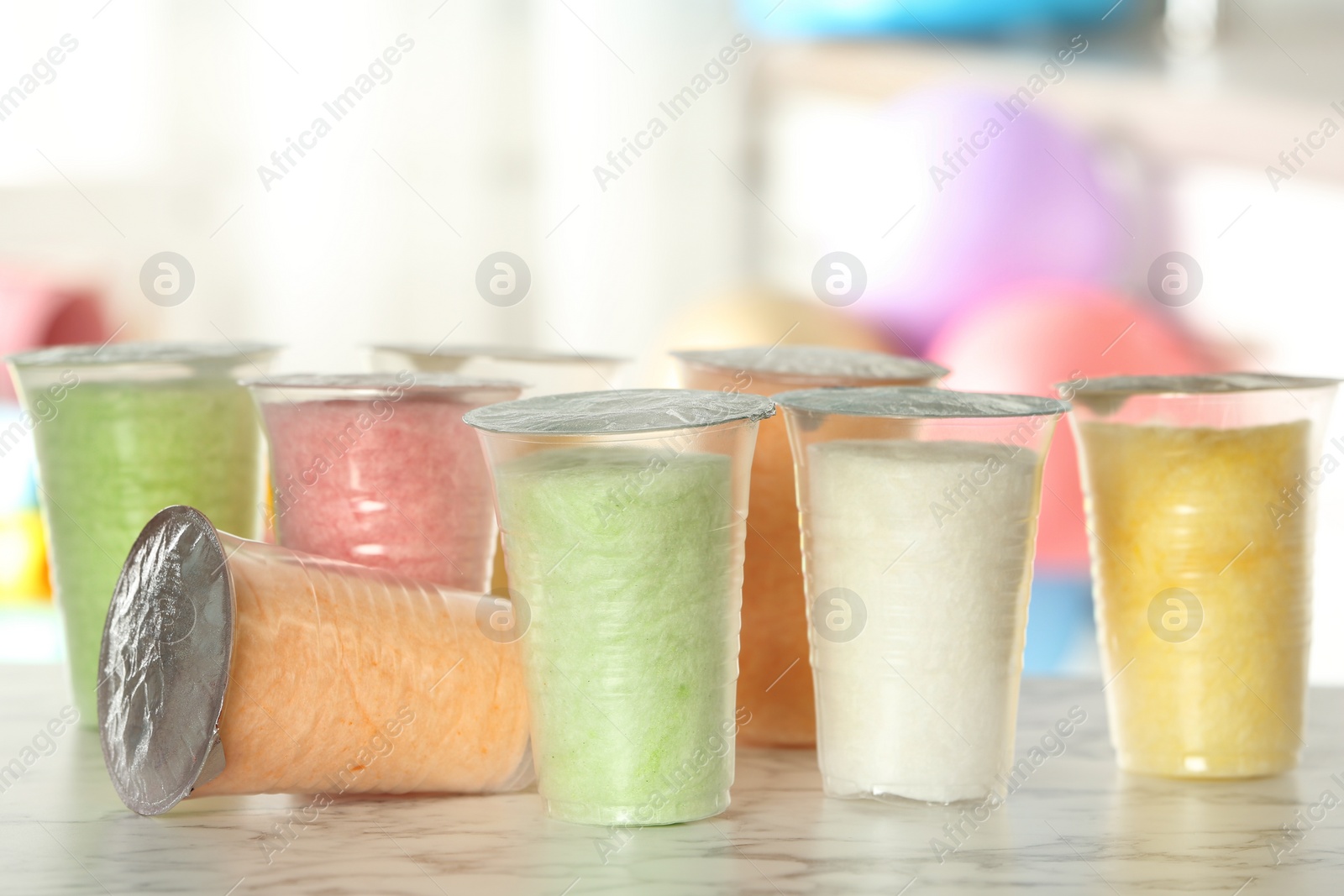 Photo of Plastic cups with cotton candy on table against blurred background