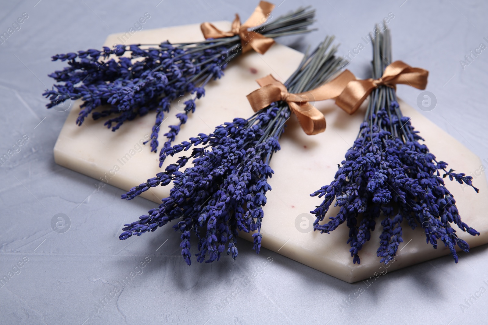 Photo of Bouquets of beautiful preserved lavender flowers and stone board on light grey textured table
