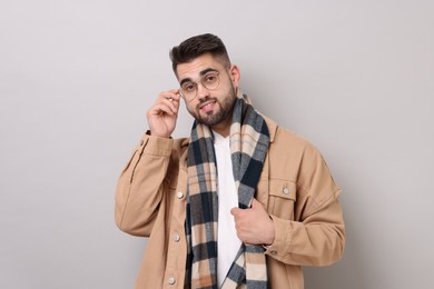 Photo of Handsome man in warm scarf on light grey background