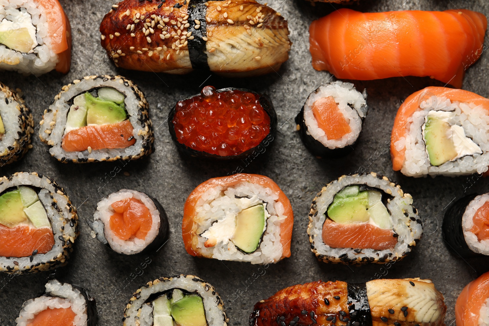 Photo of Different tasty sushi rolls on grey table, flat lay