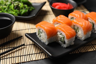 Photo of Tasty sushi rolls served on black table, closeup