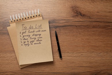 Notebook and to do list with pen on wooden table, flat lay. Space for text