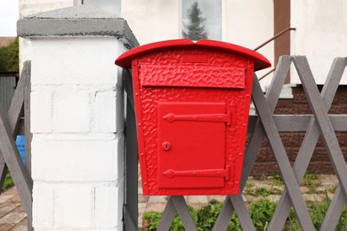 Photo of Beautiful red mailbox on grey fence outdoors