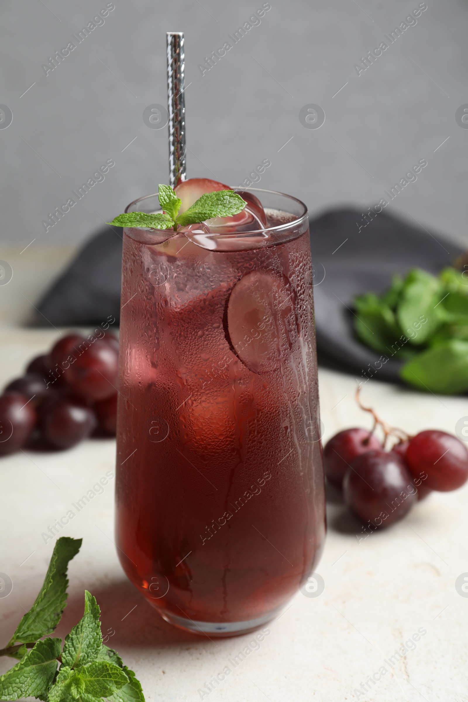 Photo of Delicious grape soda water with mint on white table. Refreshing drink