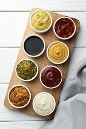 Photo of Many different sauces in bowls on white wooden table, top view