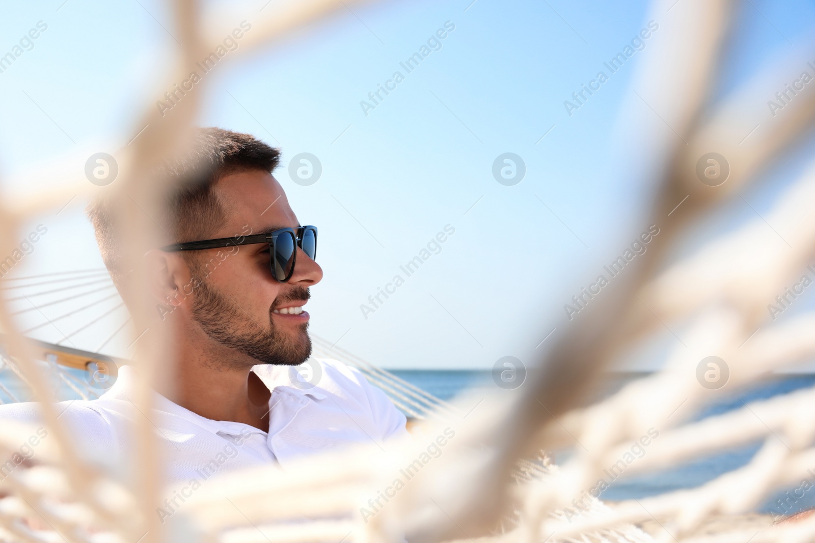 Photo of Young man relaxing in hammock on beach