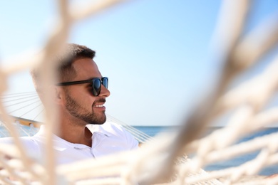 Young man relaxing in hammock on beach