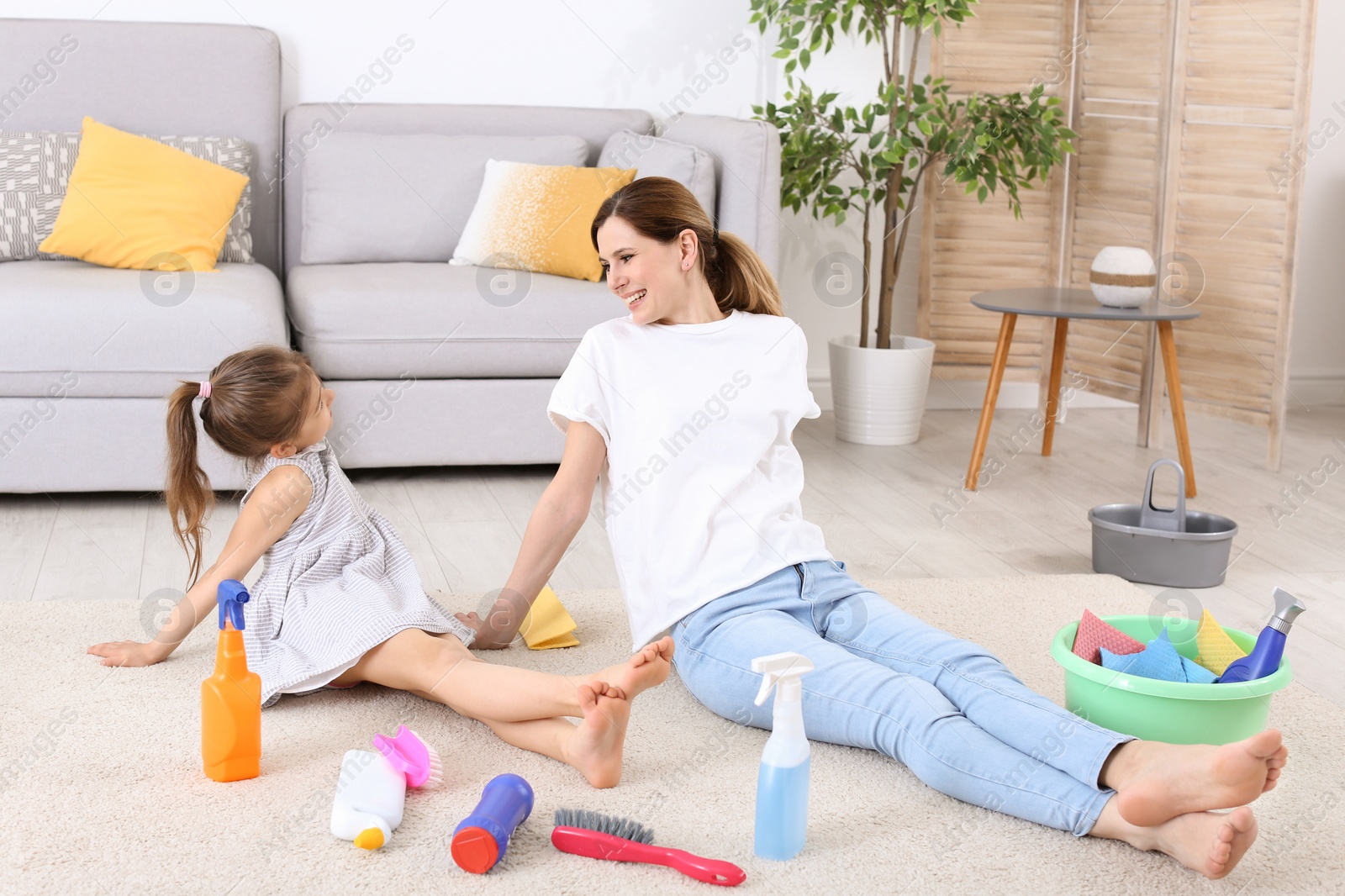 Photo of Housewife and daughter resting after cleaning in room