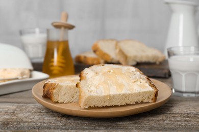 Photo of Slices of bread with butter, honey and milk on wooden table