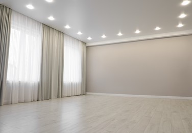 Empty room with beige wall, large window and wooden floor