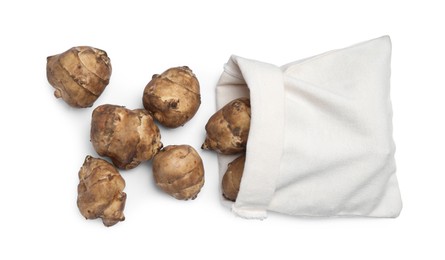 Photo of Bag and many Jerusalem artichokes isolated on white, top view