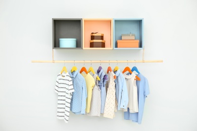 Rack with different clothes on light background