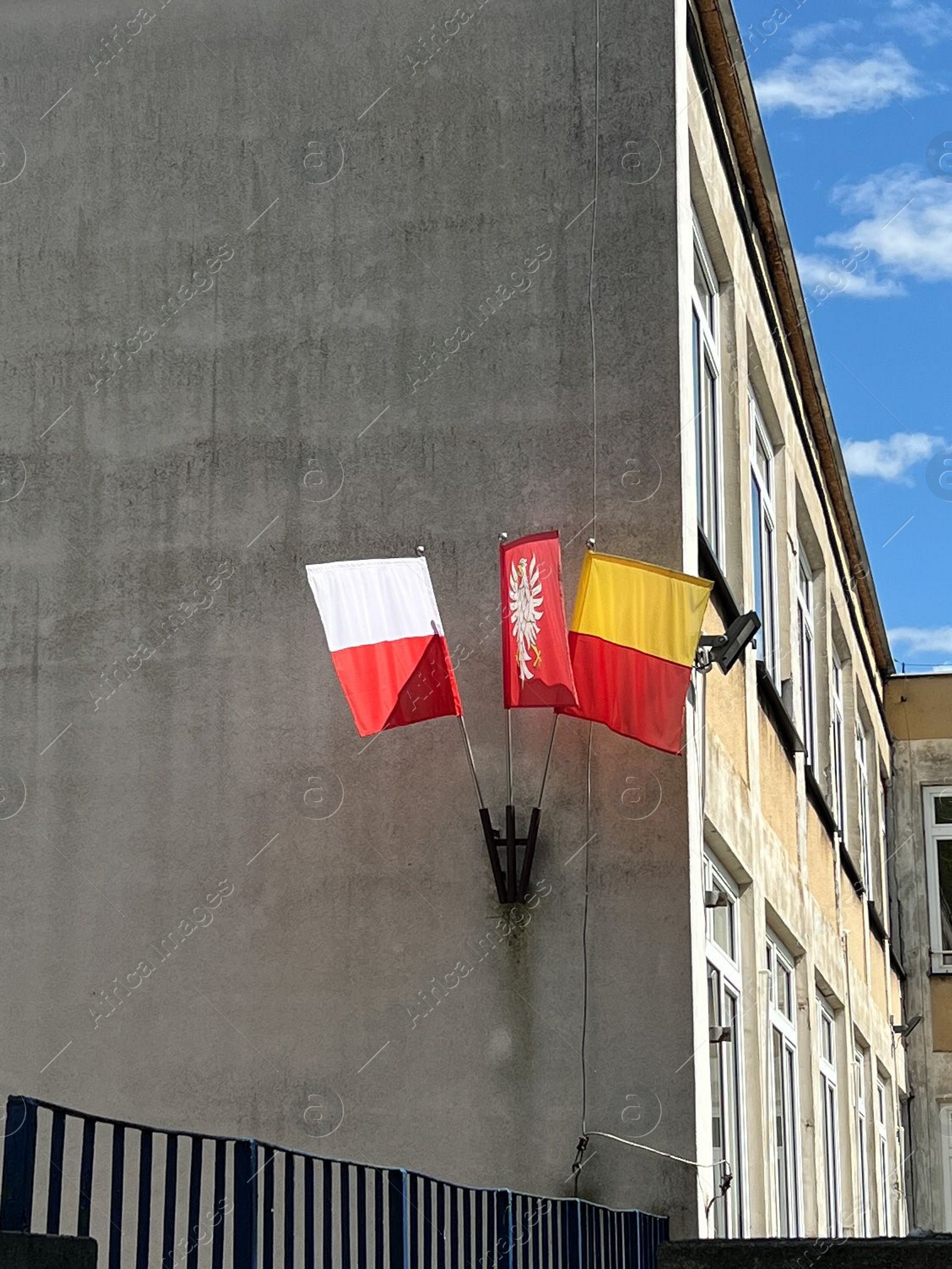 Photo of WARSAW, POLAND - JULY 17, 2022: Building facade with different flags on sunny day