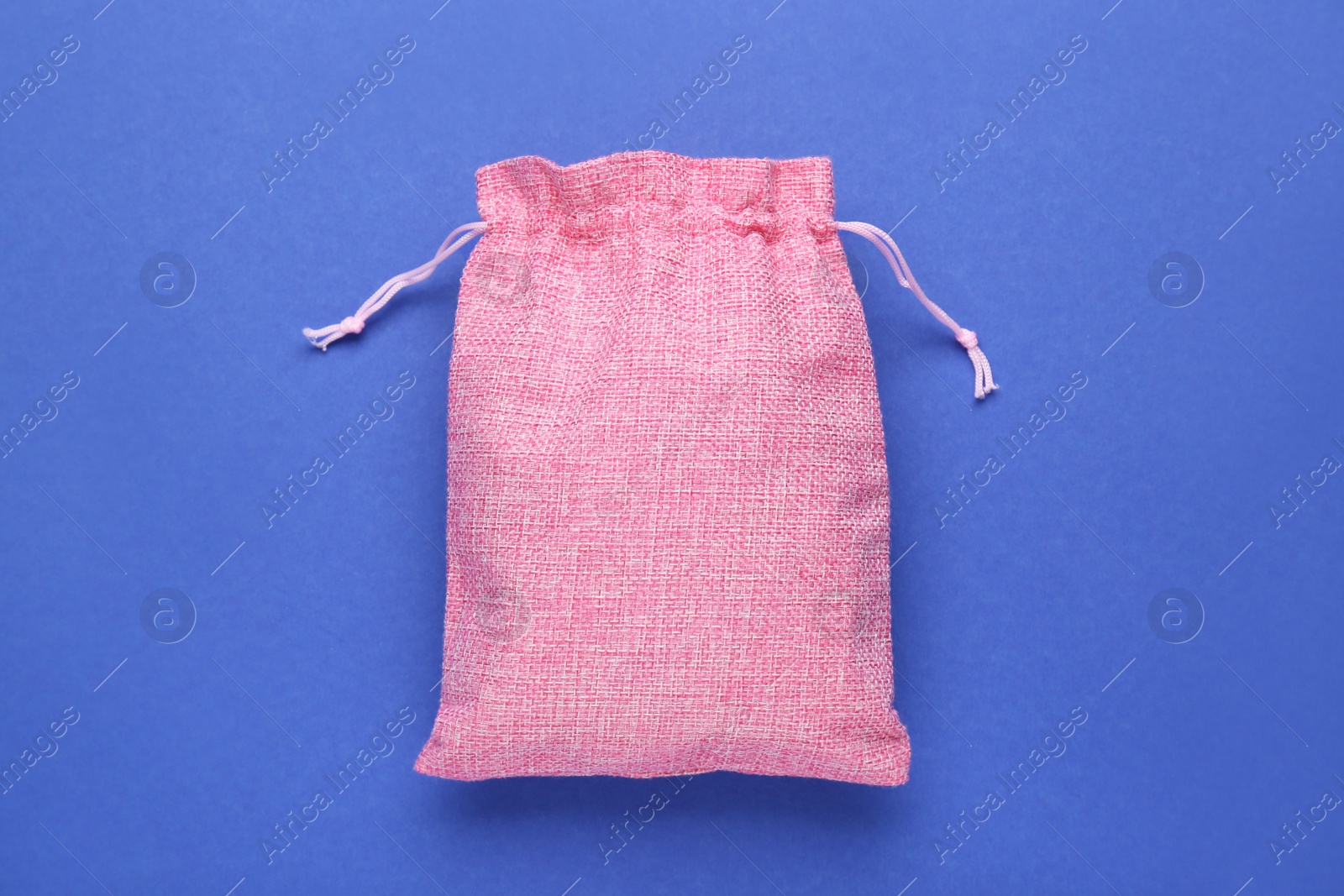 Photo of Pink burlap bag on blue background, top view