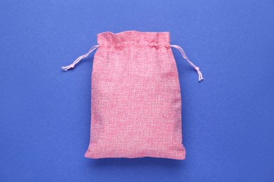 Pink burlap bag on blue background, top view