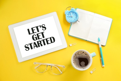 Image of Let's Get Started. Flat lay composition with tablet and stationery on yellow background