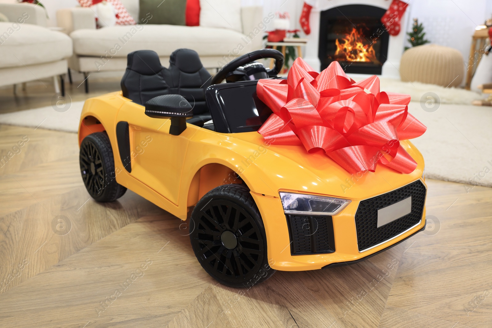 Photo of Children's electric toy car with red bow in room decorated for Christmas