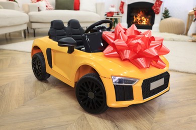 Children's electric toy car with red bow in room decorated for Christmas