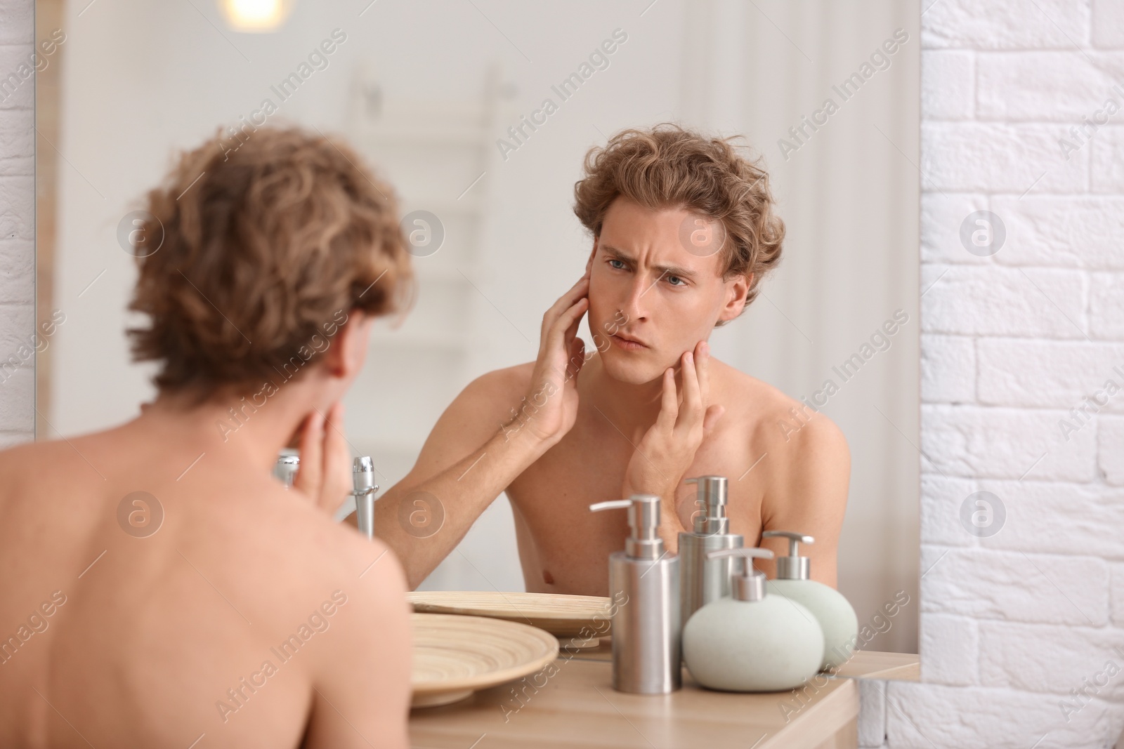 Photo of Young man looking in mirror after shaving at home