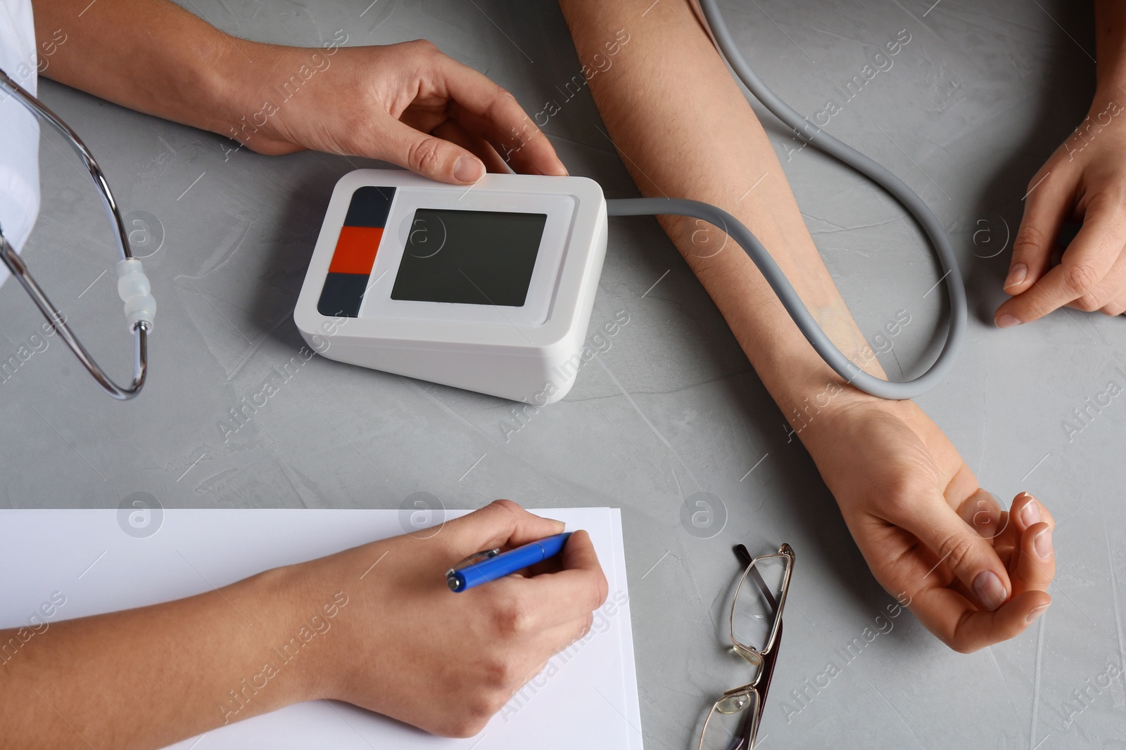 Photo of Doctor measuring blood pressure of woman in clinic, closeup. Medical service