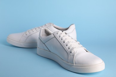 Photo of Pair of stylish white sneakers on light blue background