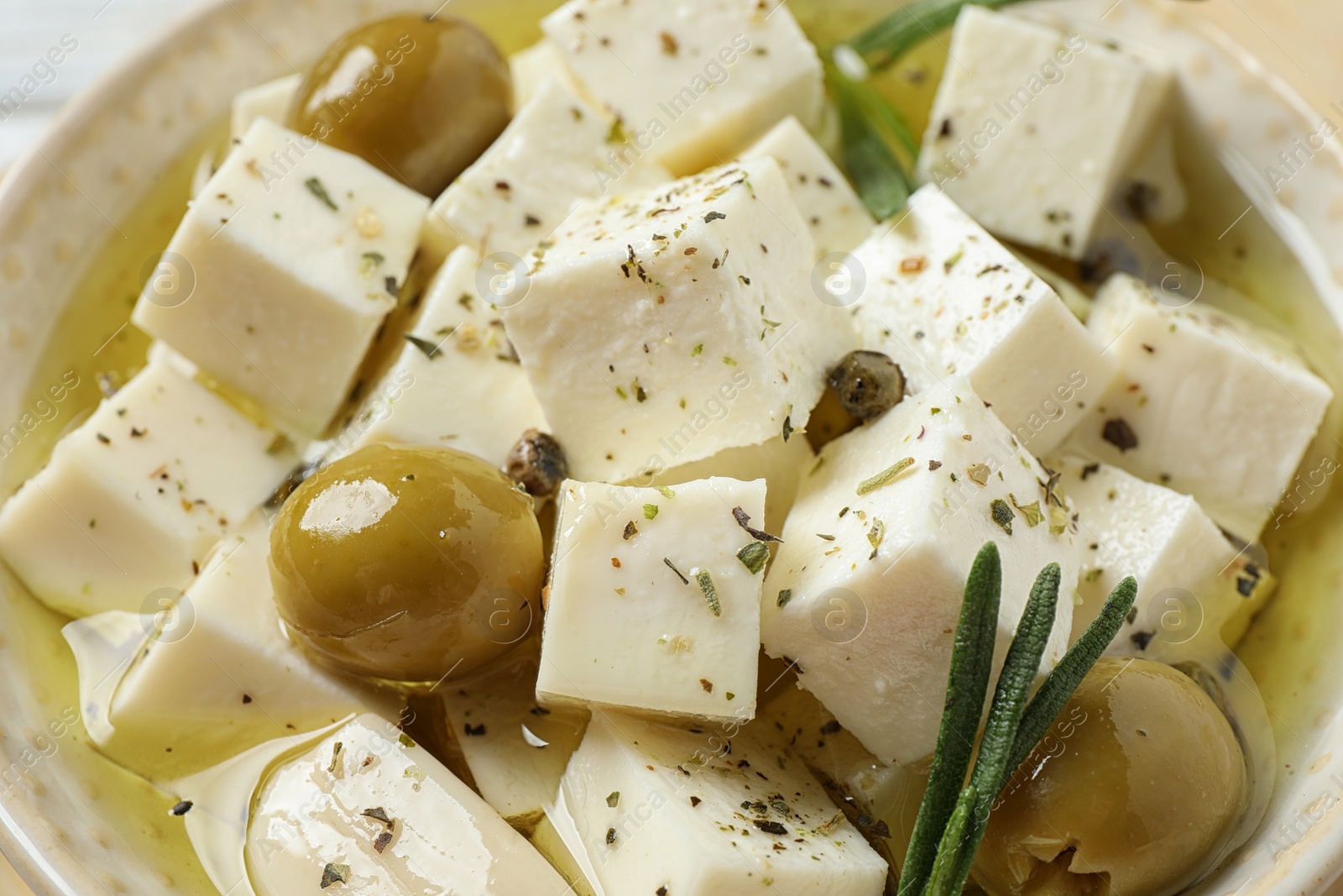 Photo of Pickled feta cheese with olives in bowl, closeup