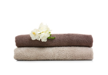 Photo of Clean folded towels with flowers on white background