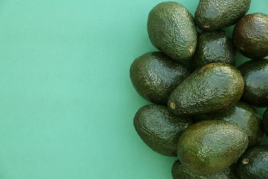 Photo of Many tasty ripe avocados on turquoise background, top view. Space for text