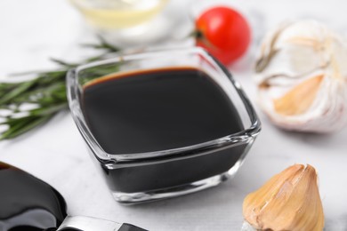 Photo of Organic balsamic vinegar and cooking ingredients on white table, closeup