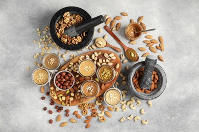 Photo of Making nut butters from different nuts. Flat lay composition on light grey table