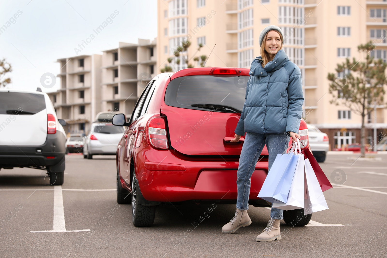 Photo of Woman with shopping bags near her car outdoors