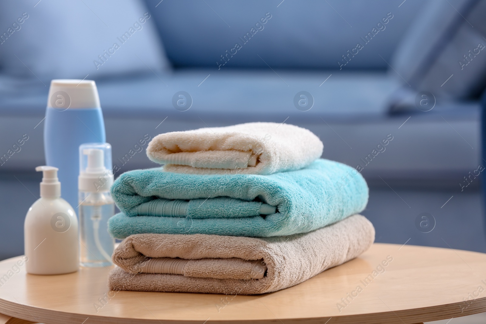 Photo of Stack of clean towels and toiletries on table indoors
