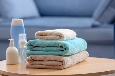 Stack of clean towels and toiletries on table indoors