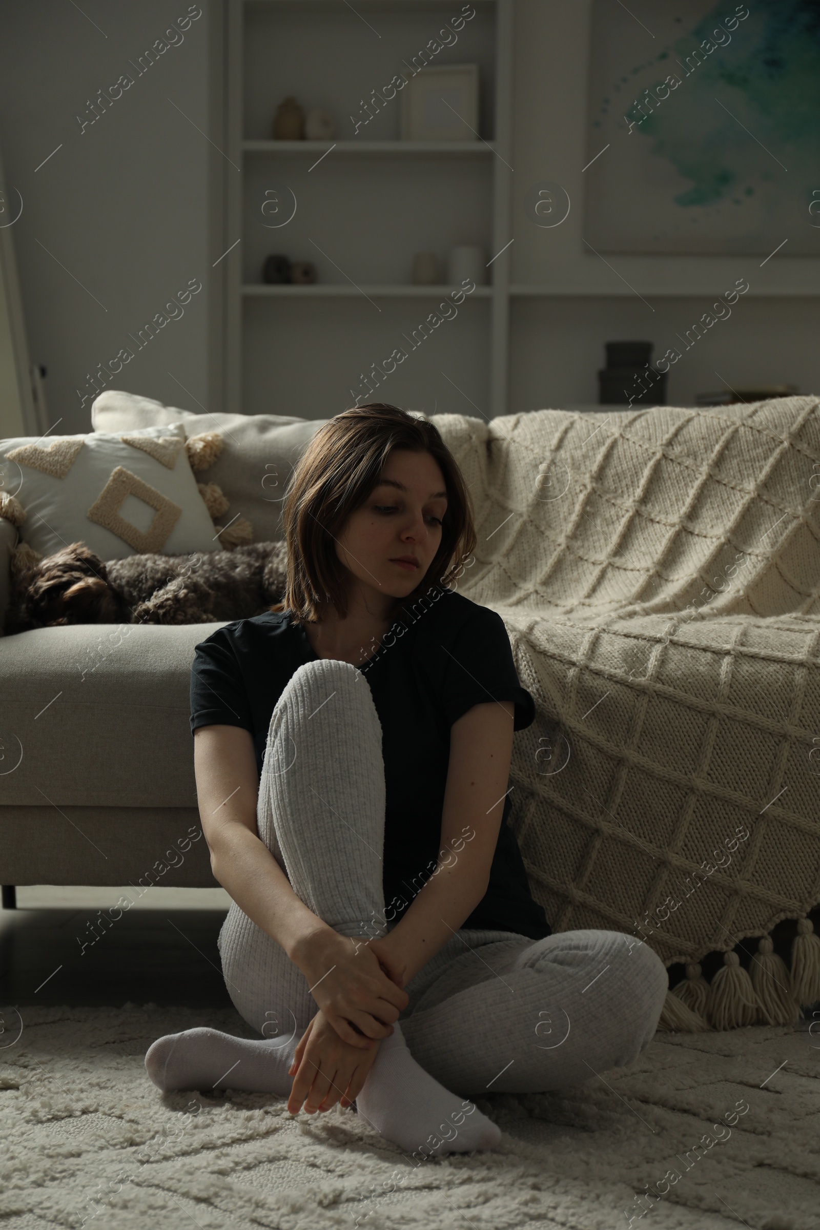 Photo of Sad young woman and her dog at home
